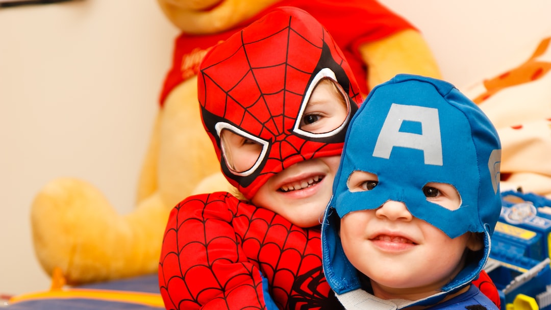 Two little boys in super heroes dresses with "Pooh" stuffed toy.