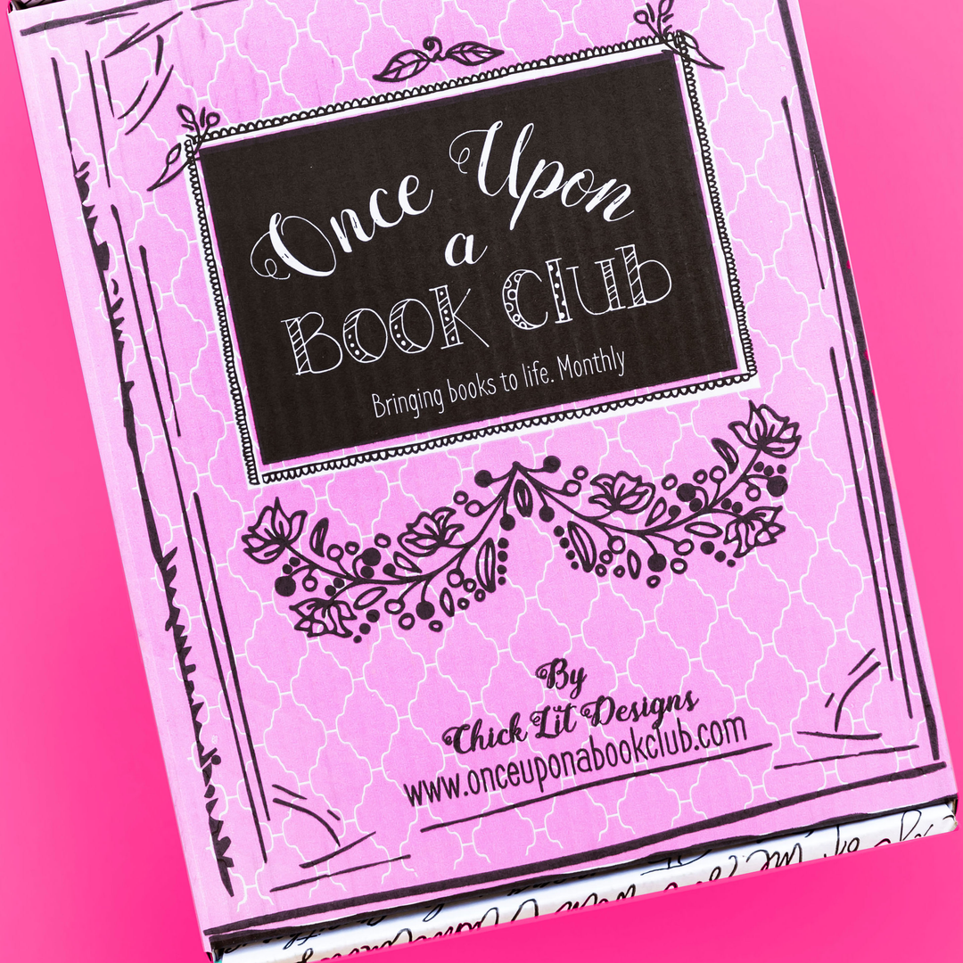 A pastel pink "Once Upon a Book Club" box with floral designs and a black label lies against a vibrant pink background.