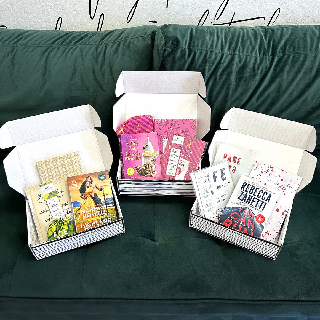 Three open boxes filled with books and themed items are displayed on a dark green sofa. Each box features different genres and gifts.
