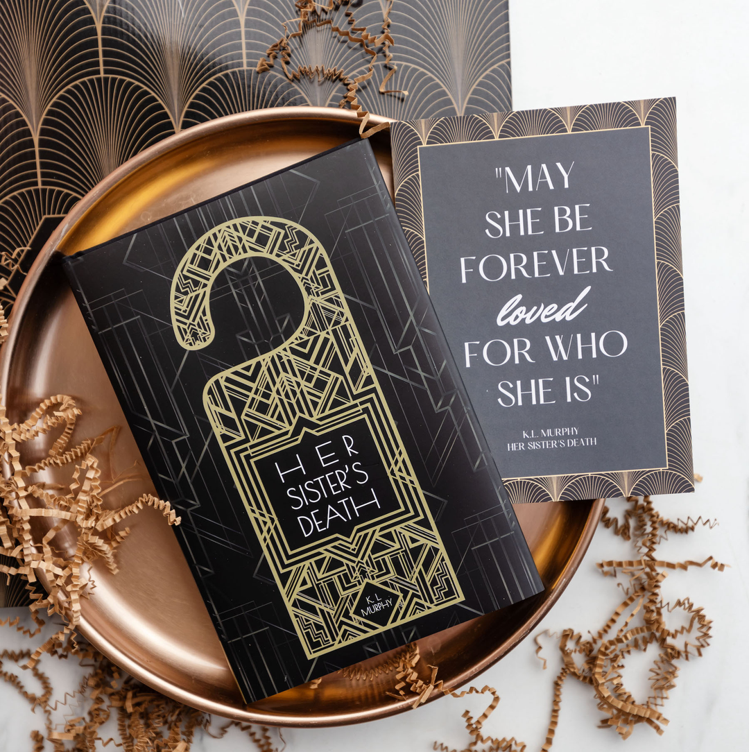 "Her Sister's Death" book with a black and gold Art Deco design, paired with a quote card, displayed on a bronze decorative tray.