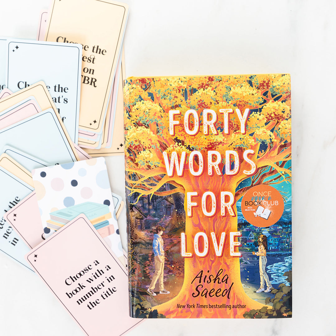 A hardcover copy of Forty Words for Love sits on a white background. Next to the book are a splayed set of To Be Read Challenge Cards. The one at the top of the pile says "Choose a book with a number in the title"