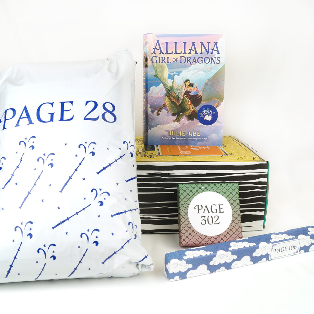 A hardcover edition of Alliana Girl of Dragons on top of a yellow box. In front of the box are a white bag, square box with dragon scales on it, and a long rectangular box with clouds on it. The boxes and bags all have page numbers.