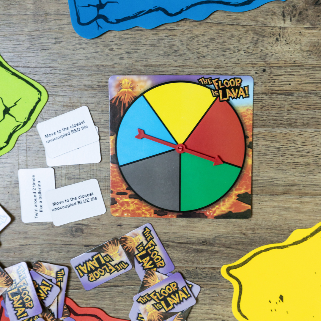 The open game of The Floor is Lava showcasing the multi-colored spinner, floor tiles, and challenge cards.