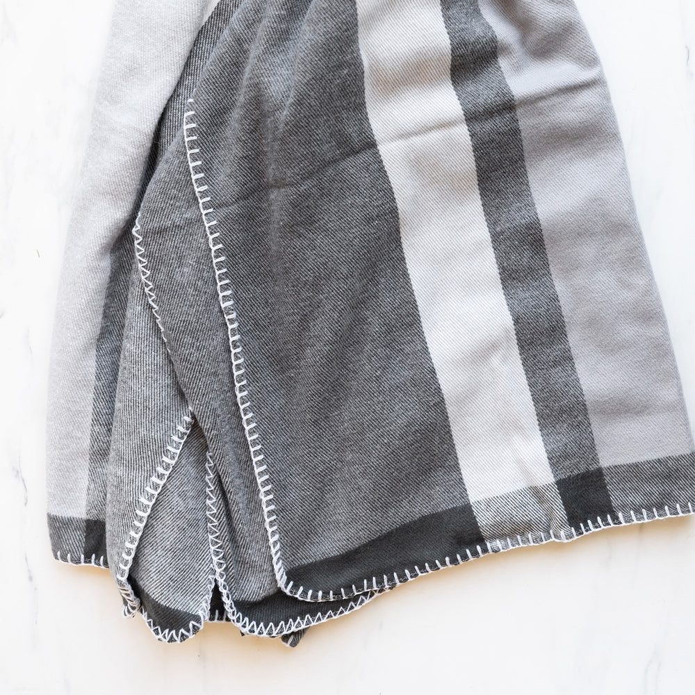 The blanket in various shades of grey, sits open on a white background.