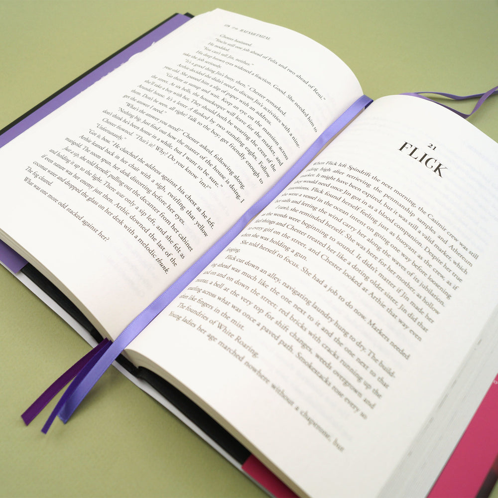 The multistrand bookmark showing multiple purple threads inside an open copy of a book.
