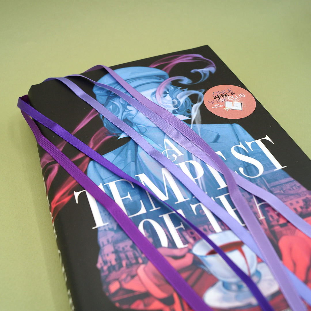 A purple multistrand bookmark sits inside a copy of A Tempest of Tea by Hafsah Faizal.