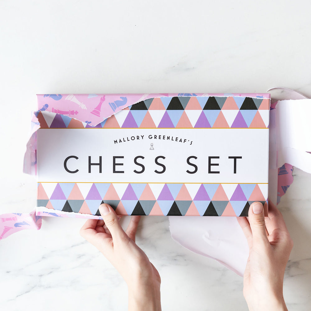 Torn pink wrapping paper reveal Mallory Greenleaf's Chess Set inspired by Check & Mate by Ali Hazelwood. Created by Once Upon a Book Club.