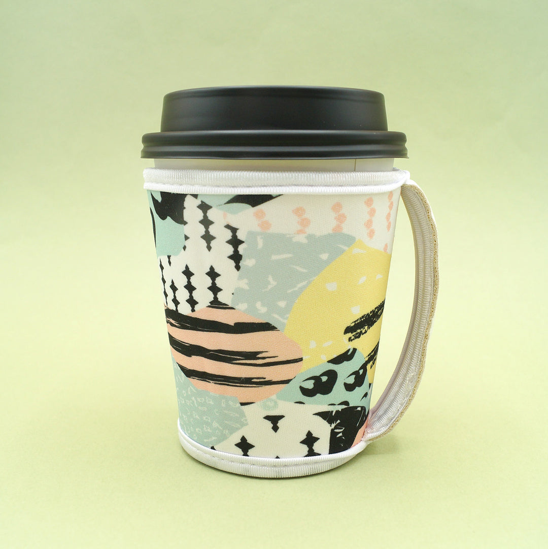 a coffee cup cozy sits on a green background with a coffee cup in it