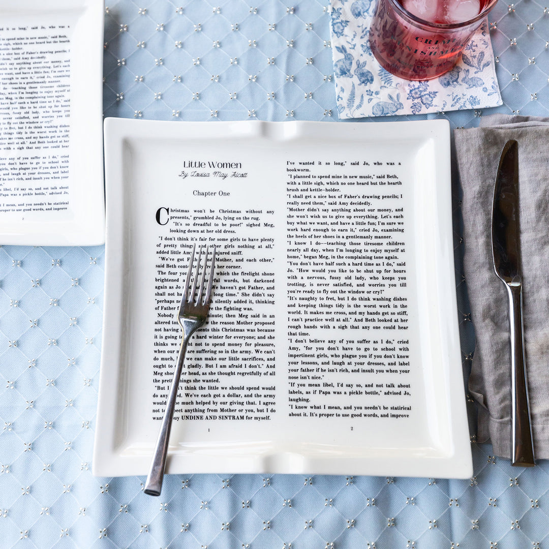 Dinner plate featuring text from Little Women Chapter One, set on a blue tablecloth with utensils.