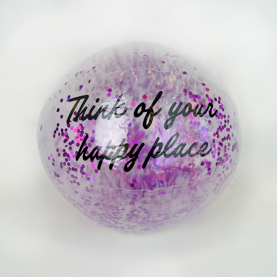a clear beach ball filled with purple sparkles that says "think of your happy place" in black writing