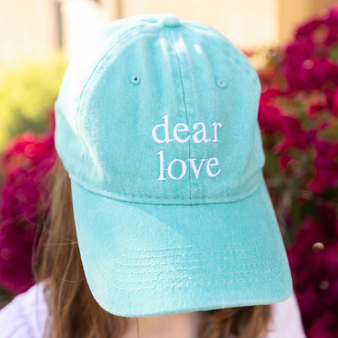 A light blue baseball hat with the words "Dear Love" embroidered on the front of it.