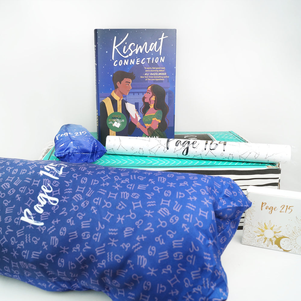 a hardcover edition of Kismat Connection sits on a green box along with a small blue drawstring bag and white tube. In front of the green box are a large blue drawstring bag with zodiac symbols on it and a small white box. The boxes and bags all have page numbers.
