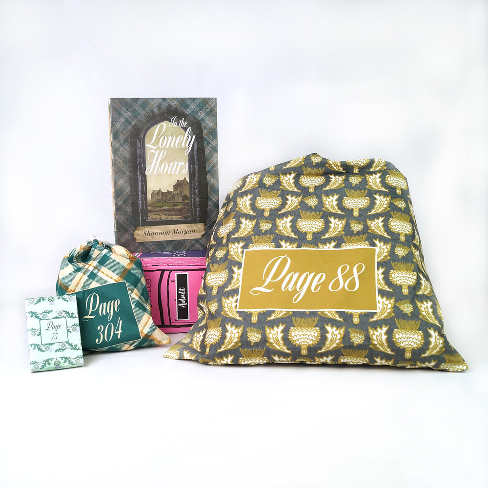 A pink Once Upon a Book Club box lays under a hardcover, exclusive edition of "In the Lonely Hours" by Shannon Morgan. Three wrapped gifts labeled with page numbers lay on the white background beneath the box in coordinating packaging.