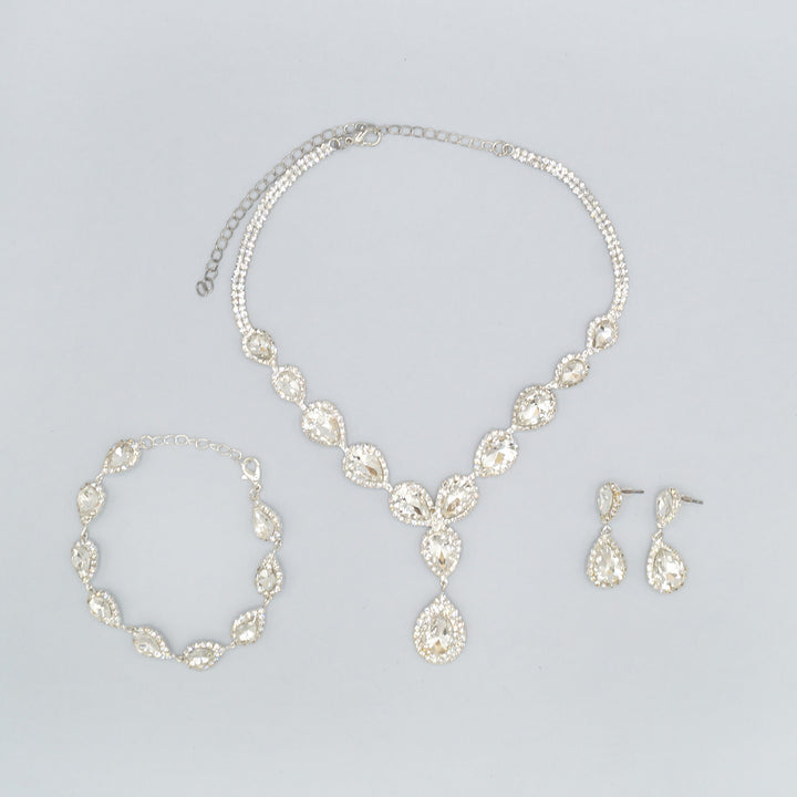 On a white background lays a pair of CZ drop earrings, CZ teardrop pendant necklace, and CZ teardrop bracelet.
