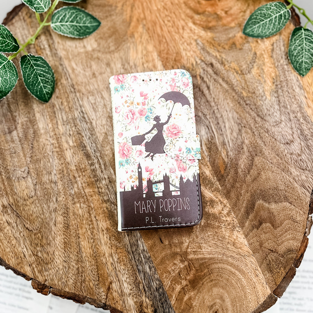 Mary Poppins clutch with floral background and London skyline on a wooden surface with green leaves.