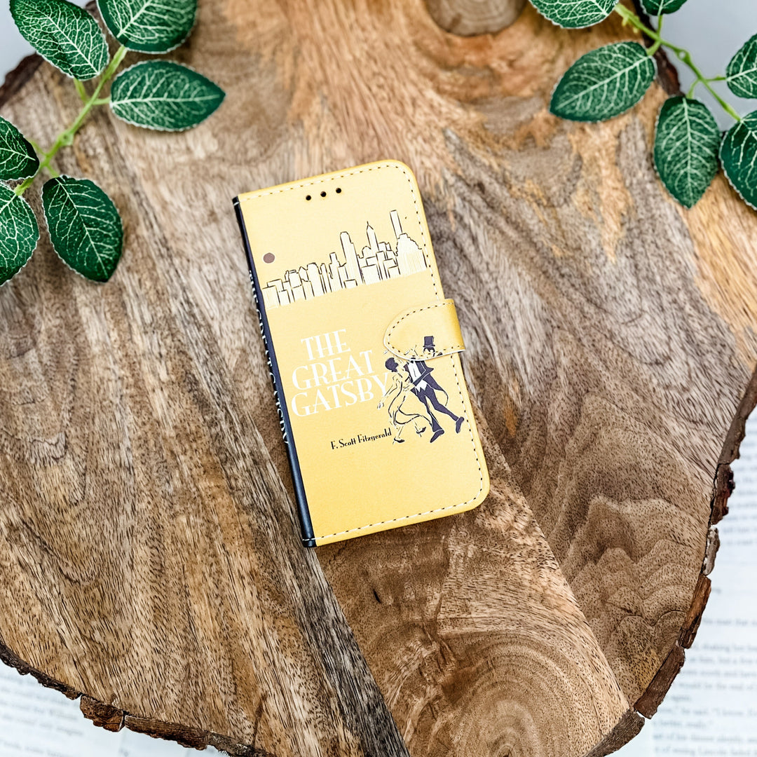 "The Great Gatsby" clutch with Art Deco design, placed on a rustic wooden surface with green leaves.