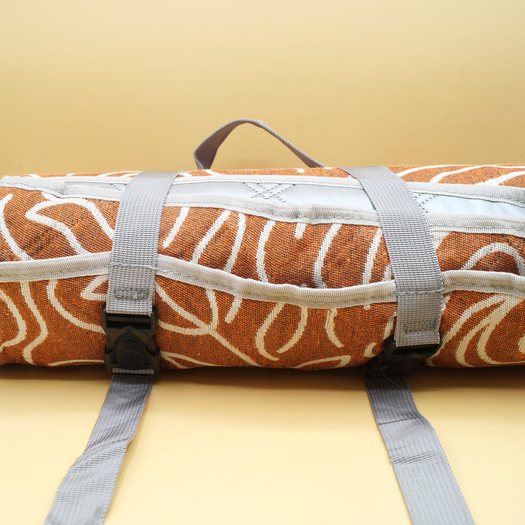 a rolled-up brown and white picnic blanket against a yellow background