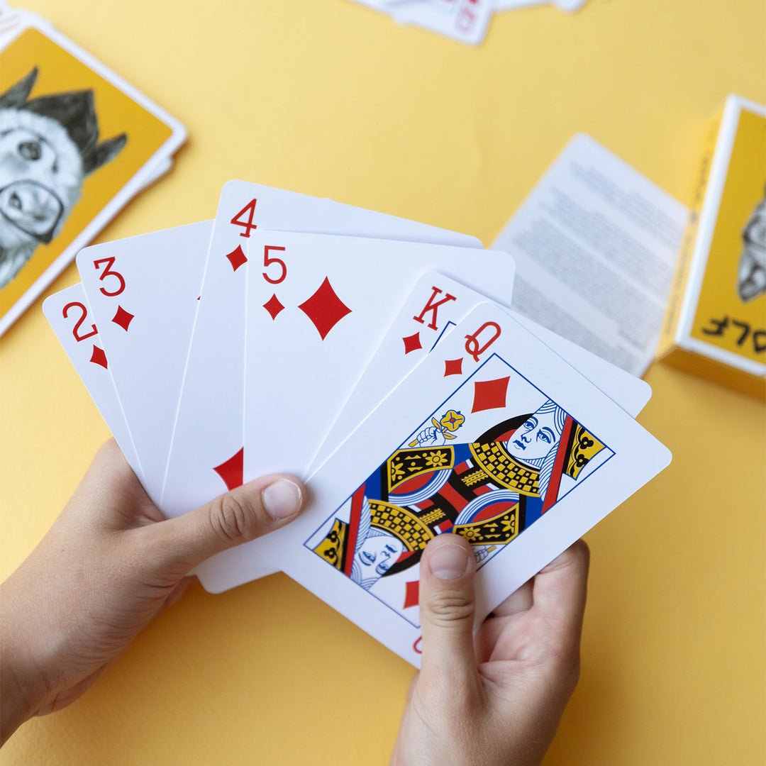 white hands hold six playing cards fanned out with the Wolf Playing Card Box in the background