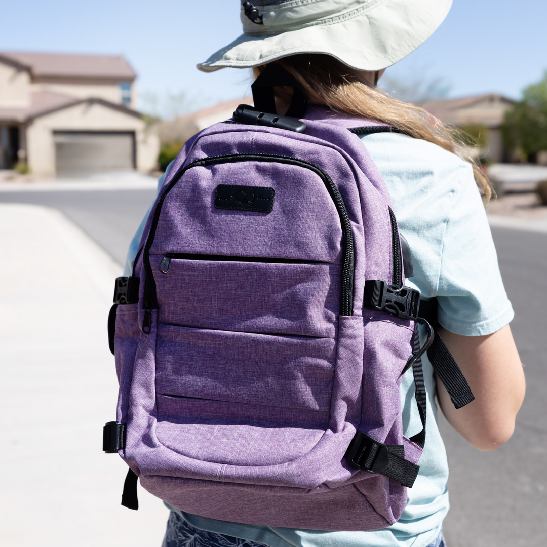 A person wearing a purple backpack displaying the Once Upon a Book Club logo in black faux leather stands outdoors.