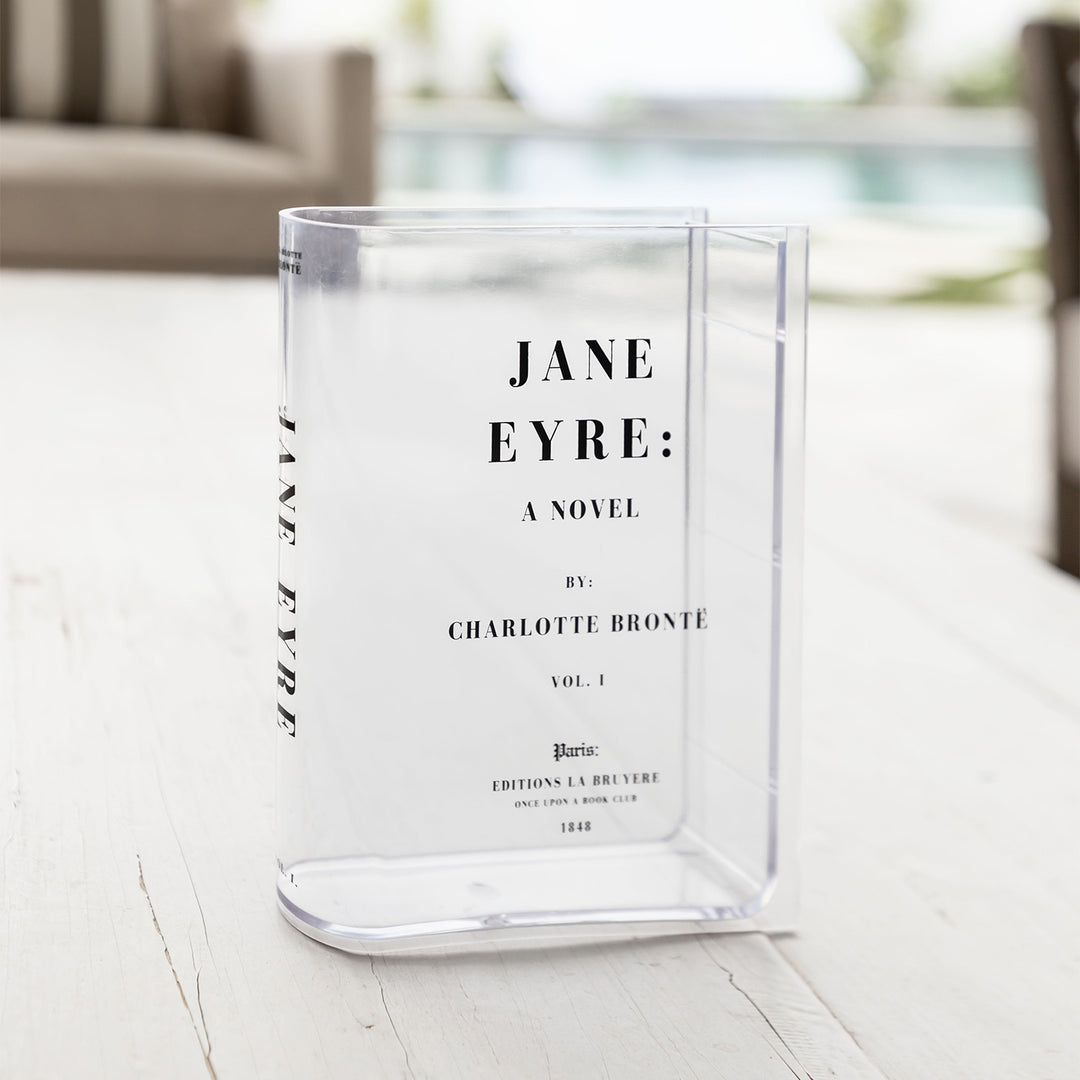 Clear acrylic vase styled as a "Jane Eyre" book cover, placed on a light wooden surface.
