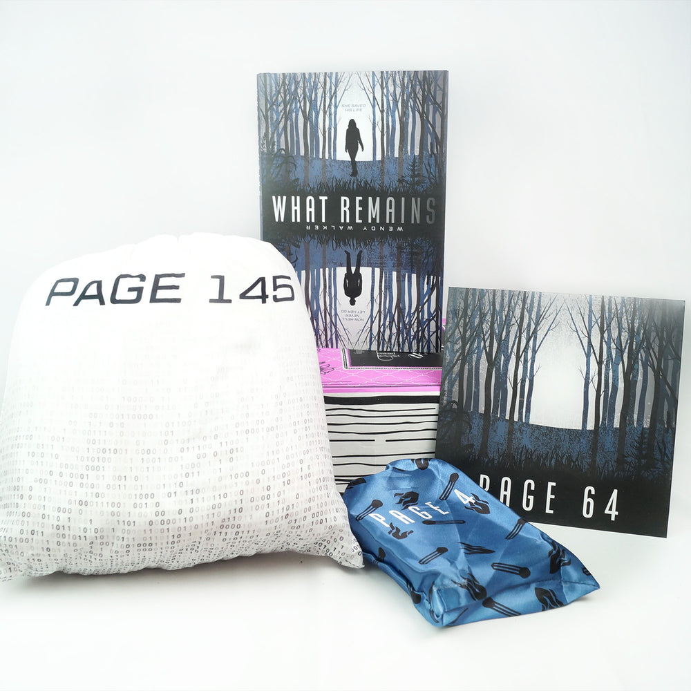 A hardcover special edition of What Remains is on a pink box. In front are a large white drawstring bag, small blue drawstring bag, and square box with a dark pattern of trees on it. The boxes and bags all have page numbers.