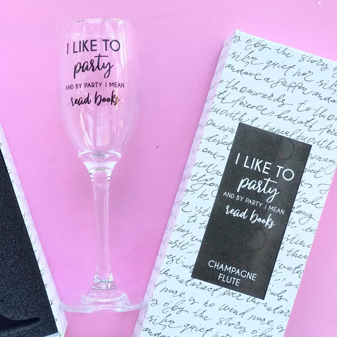 Champagne flute with "I like to party and by party I mean read books," beside matching packaging.