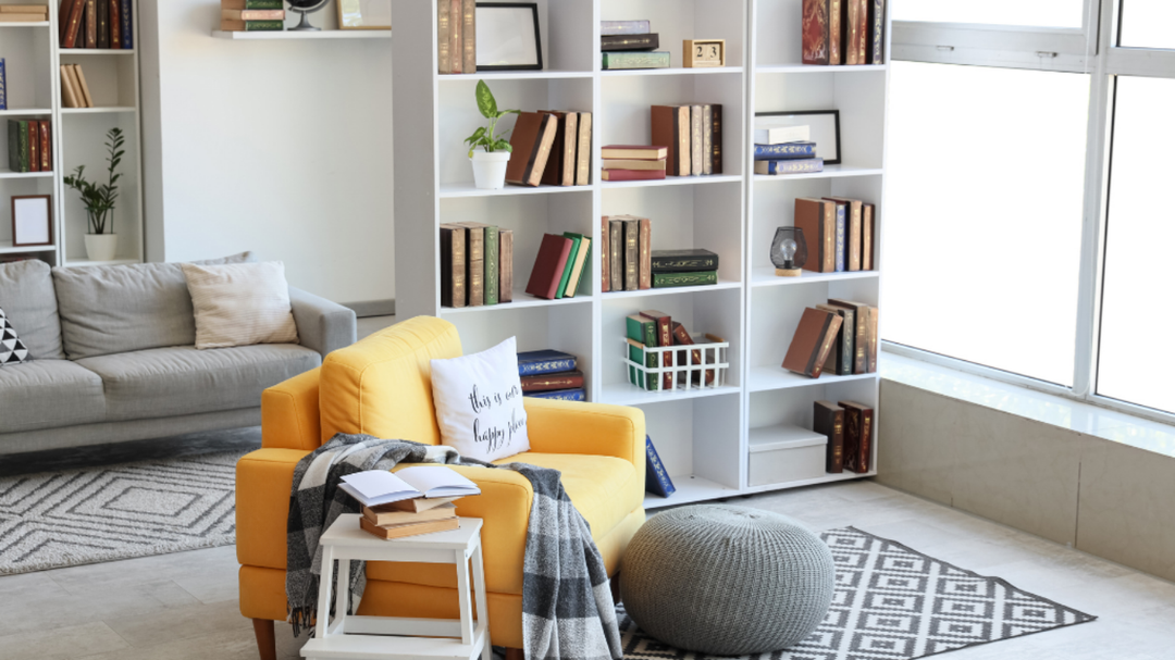 Cozy reading nook with yellow armchair, bookshelf filled with books, and soft furnishings in a bright living space.