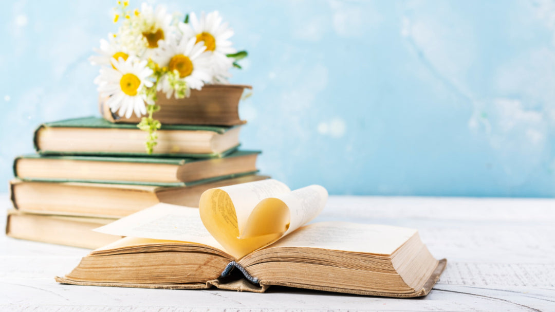  Stack of books with daisy flowers and heart-shaped pages—celebrating the beauty and love of reading on Book Lovers Day.