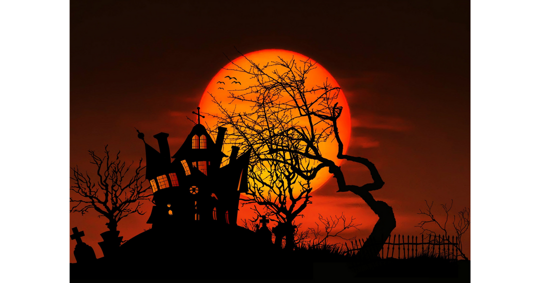 Halloween scene with a haunted house silhouetted against a large orange moon and bare trees.