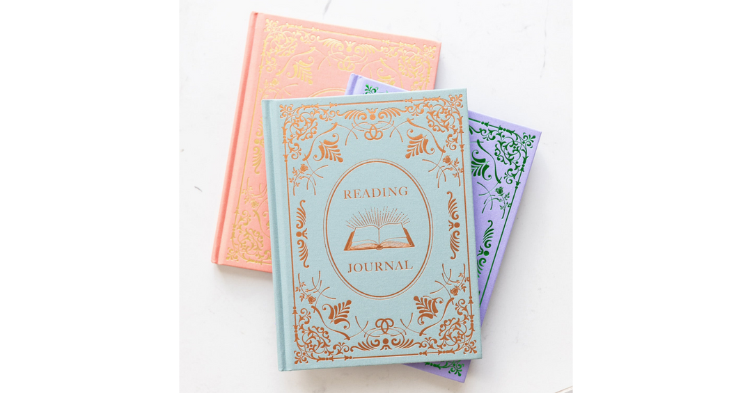 A collection of pastel-colored reading journals with ornate gold detailing stacked together on a white background.