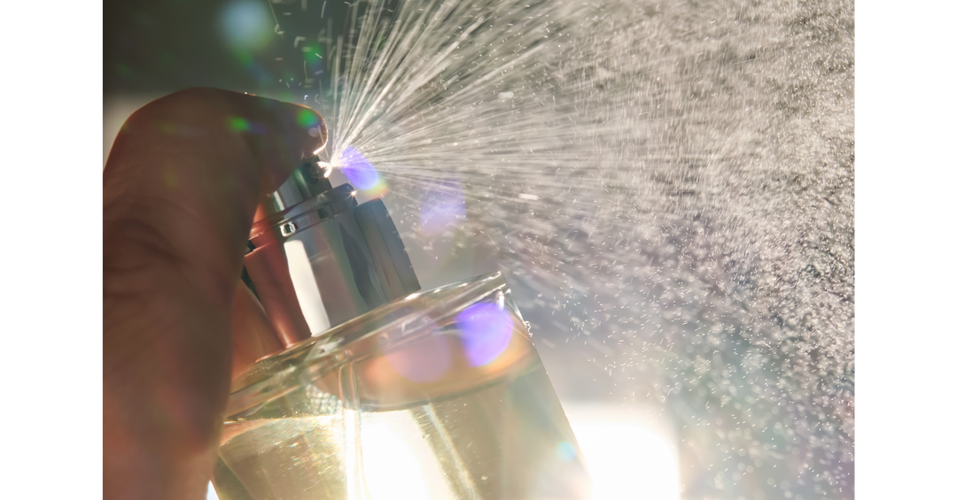 A close-up of perfume being sprayed with sparkling mist catching the sunlight for a dreamy, cinematic effect.