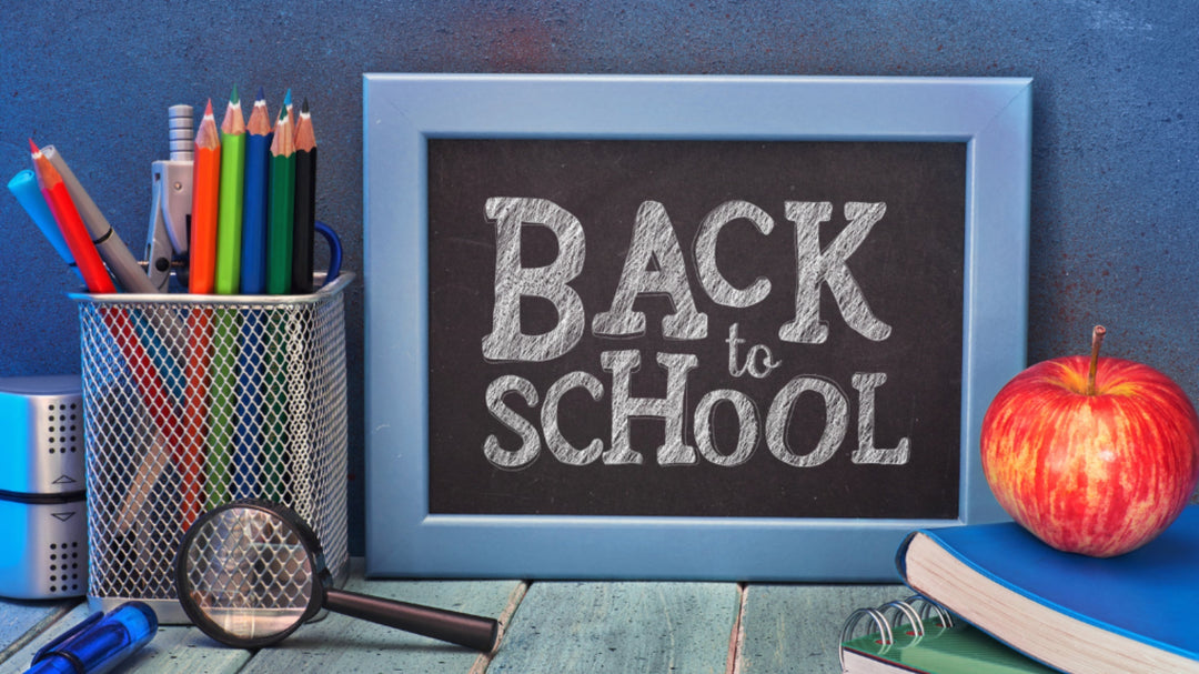 A framed chalkboard reads "BACK to SCHOOL" next to a cup of pencils, an apple on books, and a magnifying glass.