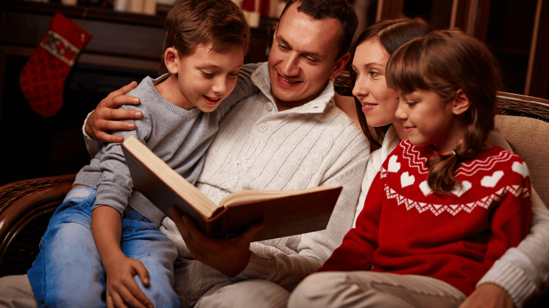 Family sitting together reading a book, smiling and enjoying a cozy moment.