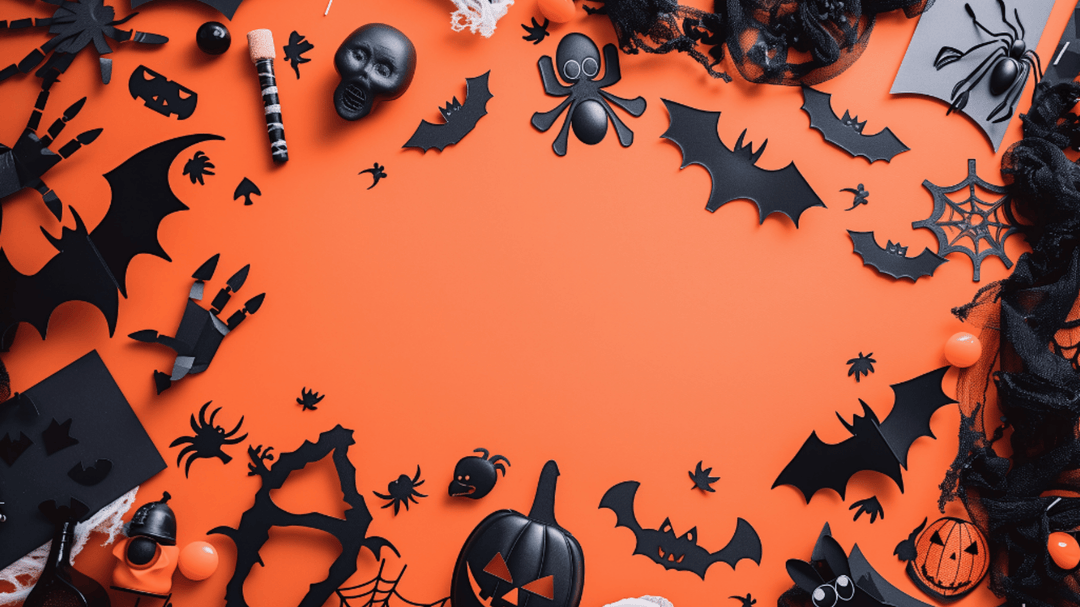 Flat lay of black Halloween decorations like bats, spiders, and skulls on an orange background.