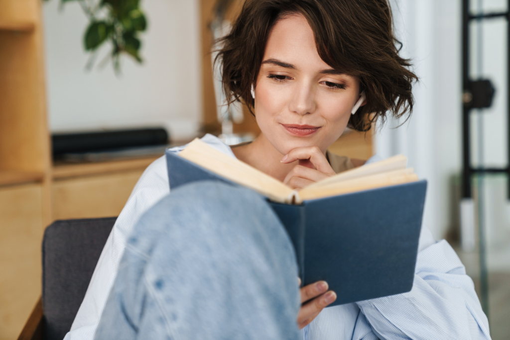 Photo of a woman sitting comfortably, reading a book and smiling thoughtfully.