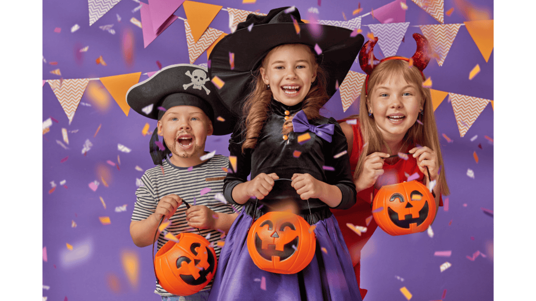 Three kids in Halloween costumes holding pumpkin buckets, with confetti and bunting on a festive purple background.