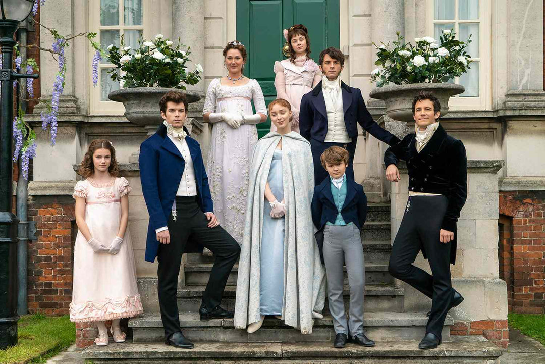 The Bridgerton family posed on elegant estate steps with Lady Violet Bridgerton at the center, surrounded by her children in Regency attire.