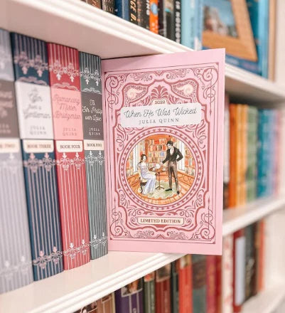 Limited edition copy of When He Was Wicked by Julia Quinn displayed on a bookshelf among other Bridgerton series books, showcasing its elegant cover design.