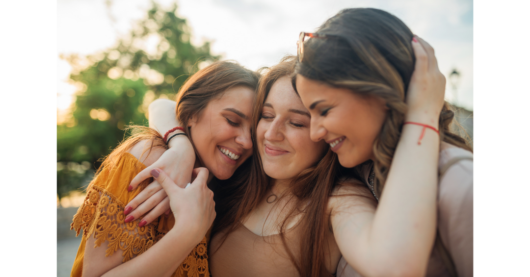 Three friends sharing a warm embrace outdoors, celebrating friendship, connection, and joyful moments together in the sunshine.