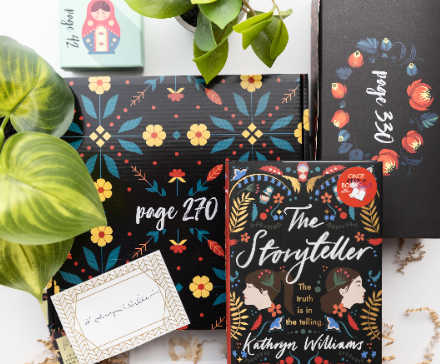 A book subscription box featuring "The Storyteller" by Kathryn Williams, packages labeled with page numbers, a note, and themed accessories, surrounded by green plants.