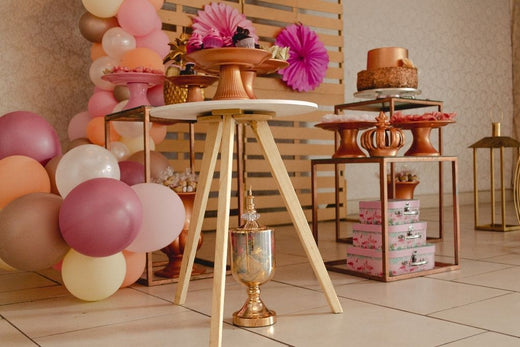 Festive party setup with balloons, cakes on stands, and floral decorations with book boxes.