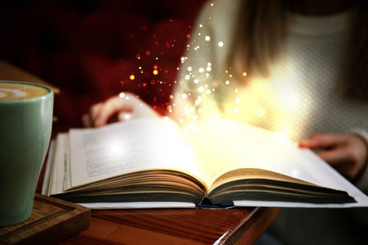 Magical glow emanating from an open book next to a coffee mug, capturing the enchantment of Once Upon a Book Club's tales.