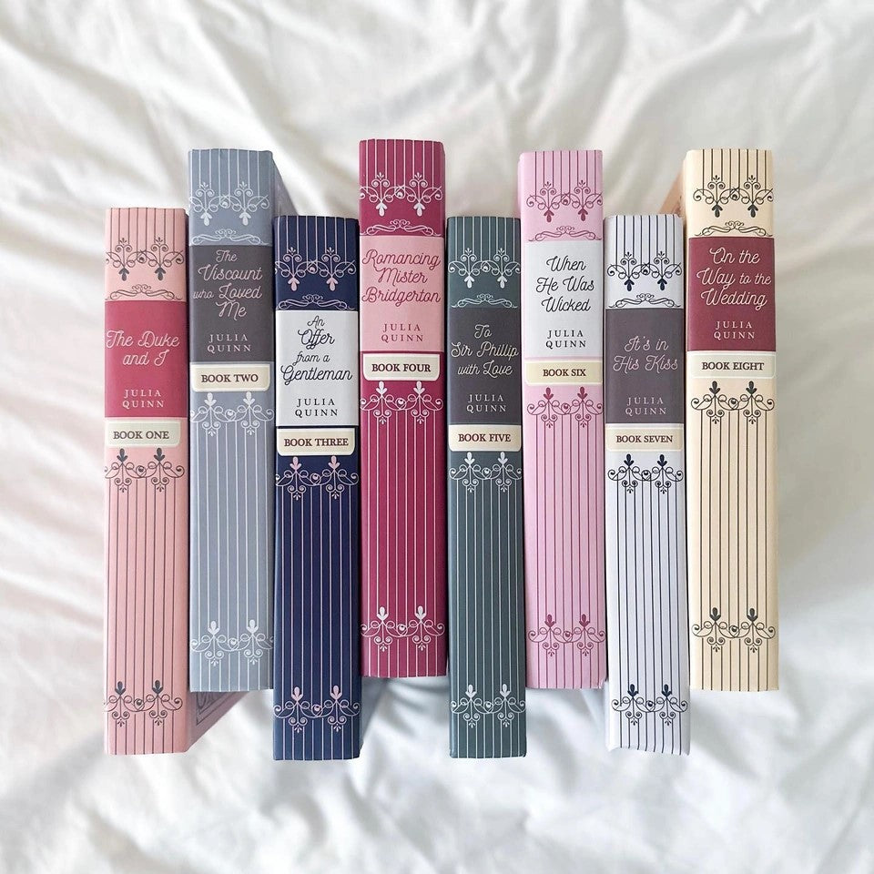 All eight limited edition Bridgerton hardcovers by Julia Quinn displayed upright on a white surface, showcasing the decorative spines in various colors.