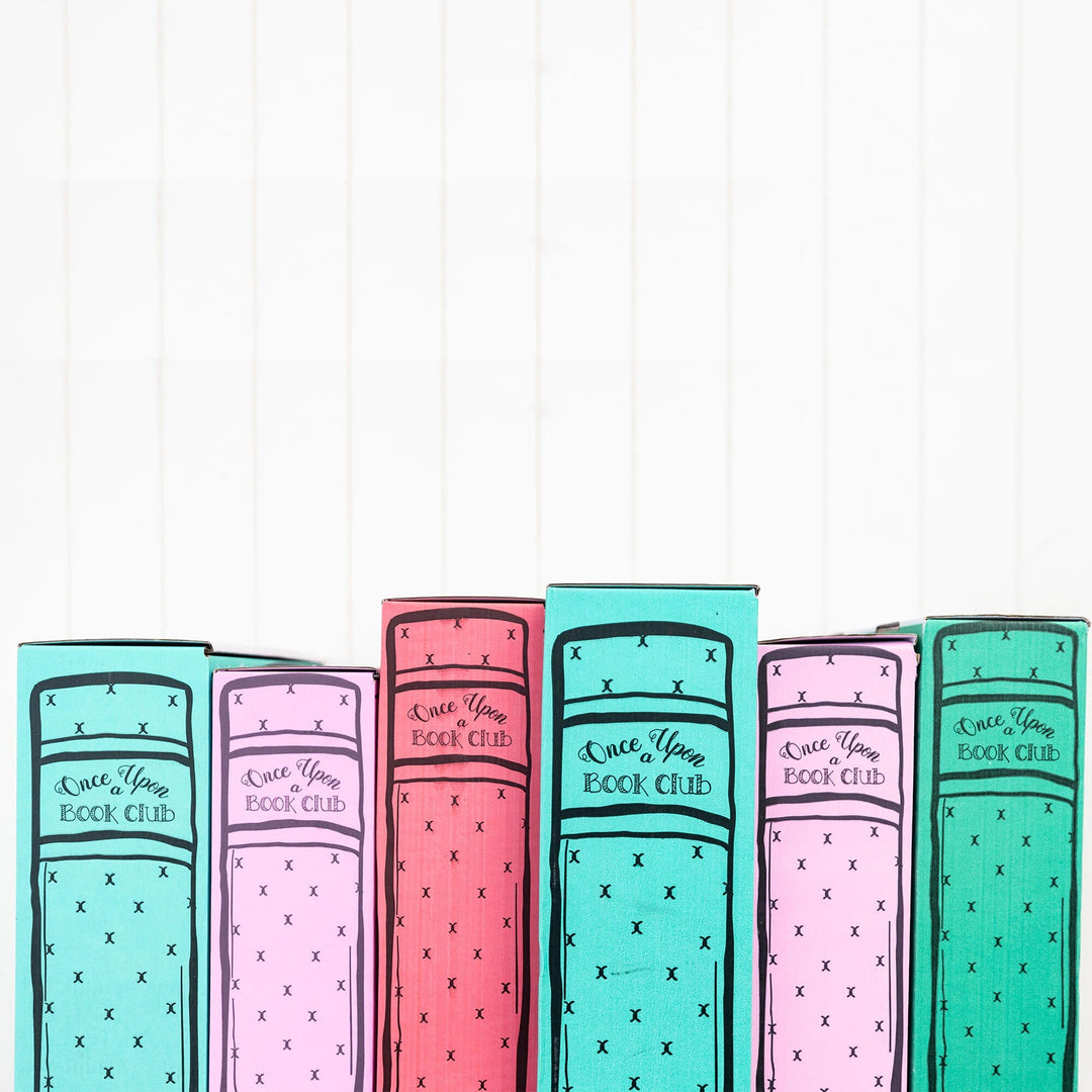 Colorful Once Upon a Book Club boxes resembling book spines are arranged upright against a white background, creating a vibrant display.