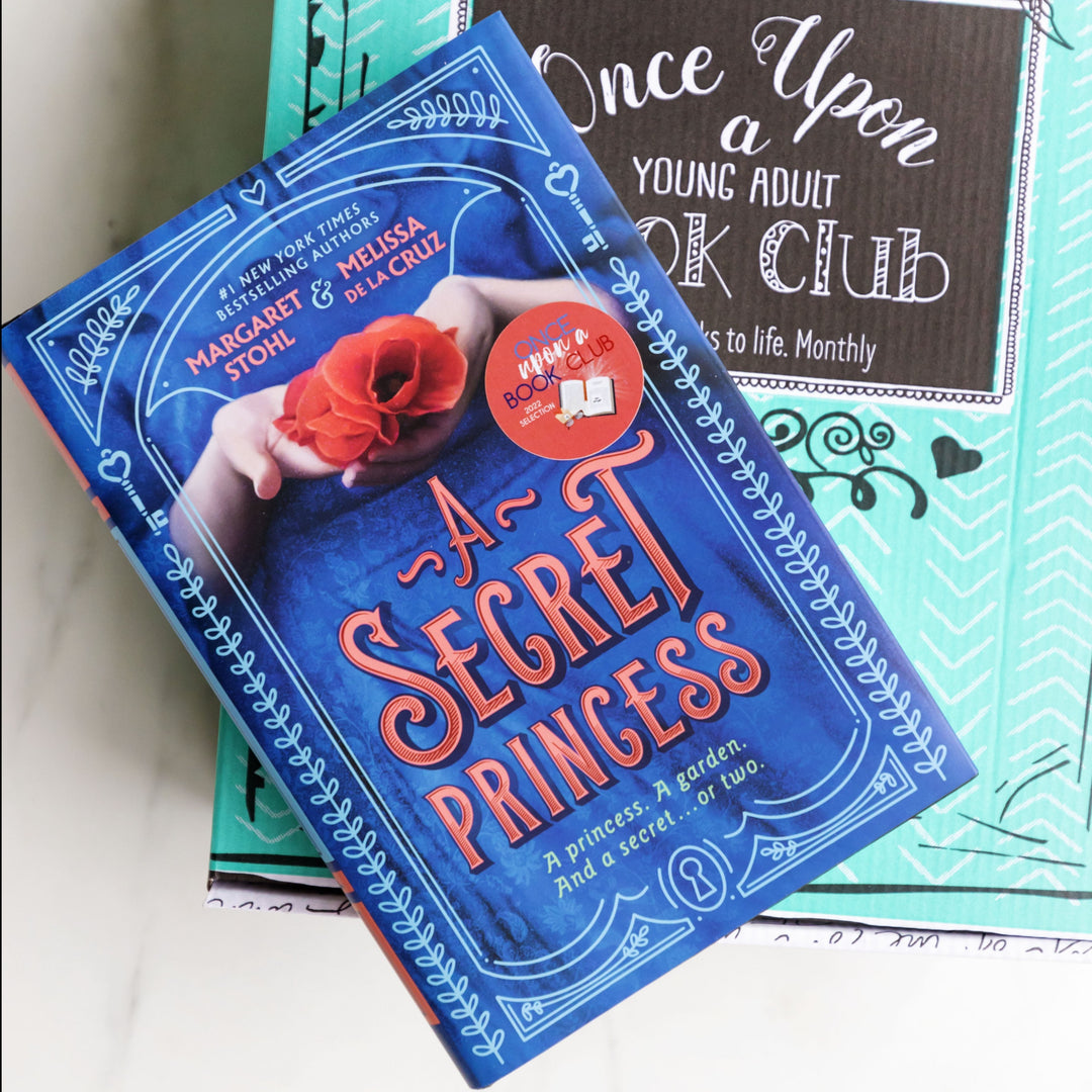 a hardcover edition of "A Secret Princess" by Margaret Stohl and Melissa de la Cruz sits on a green box