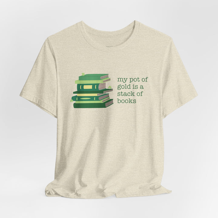 Beige t-shirt with green stack of books and clovers graphic and text "my pot of gold is a stack of books" on a white background
