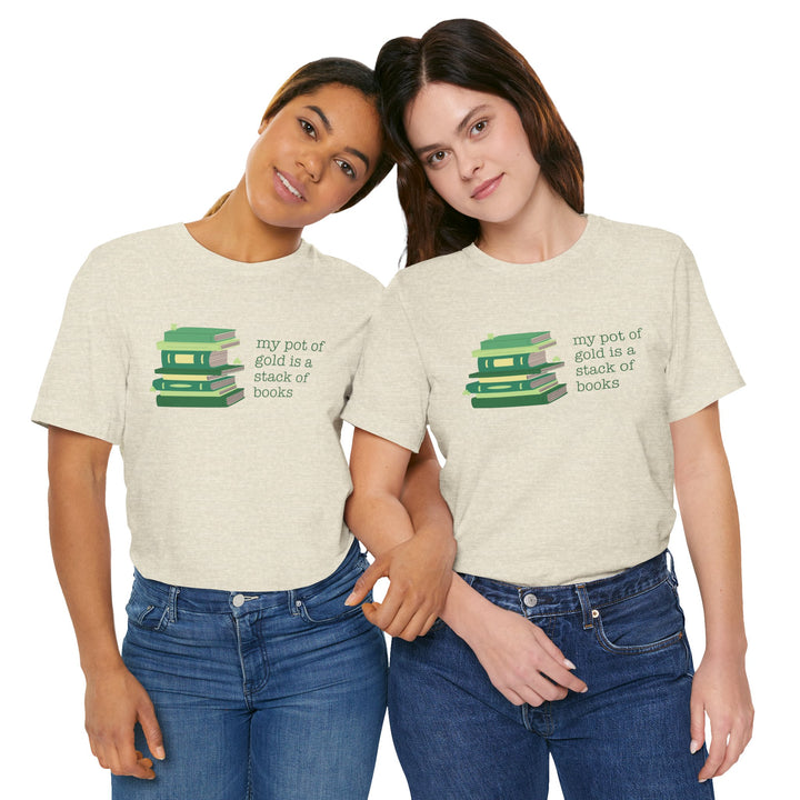 Two people wearing matching beige t-shirts with green stack of books and clovers graphic and text "my pot of gold is a stack of books" on a white background