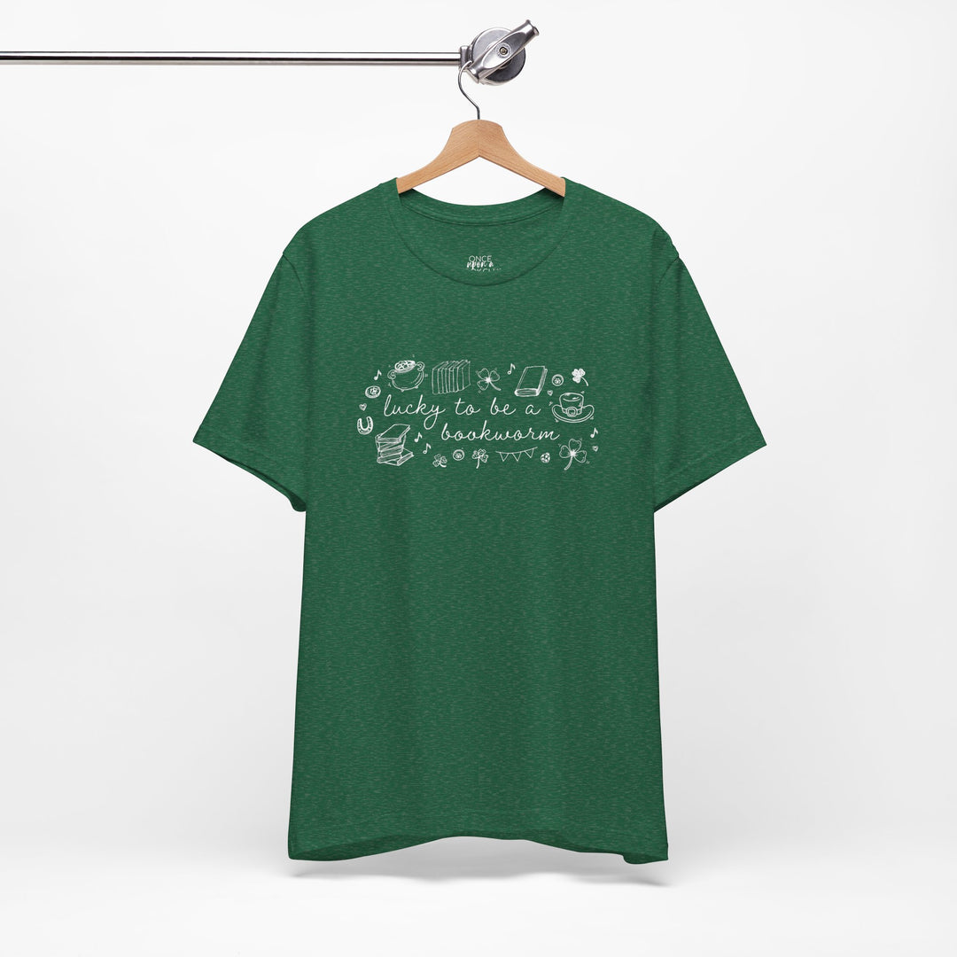 Green t-shirt with white font reading "lucky to be a bookworm" and line illustrations of St. Patrick's Day items and books on a white background