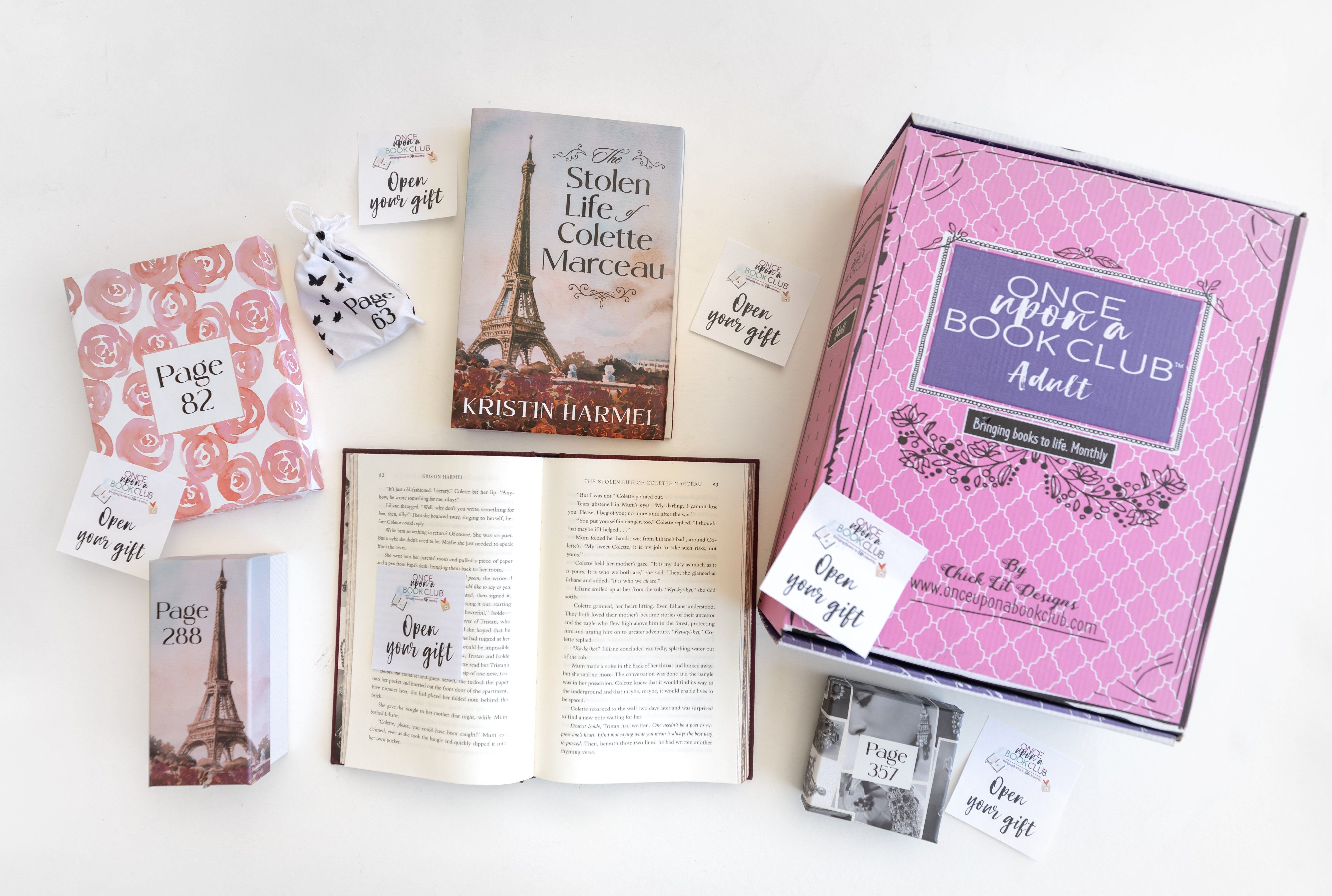 A custom edition of "The Stolen Life of Colette Marceau" by Kristin Harmel surrounded by wrapped gifts labeled with page numbers and "Open Your Gift" sticky notes on a white background