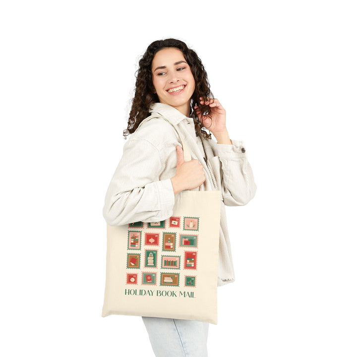 Woman holding a tote bag with 'Holiday Book Mail' stamp design on a white background